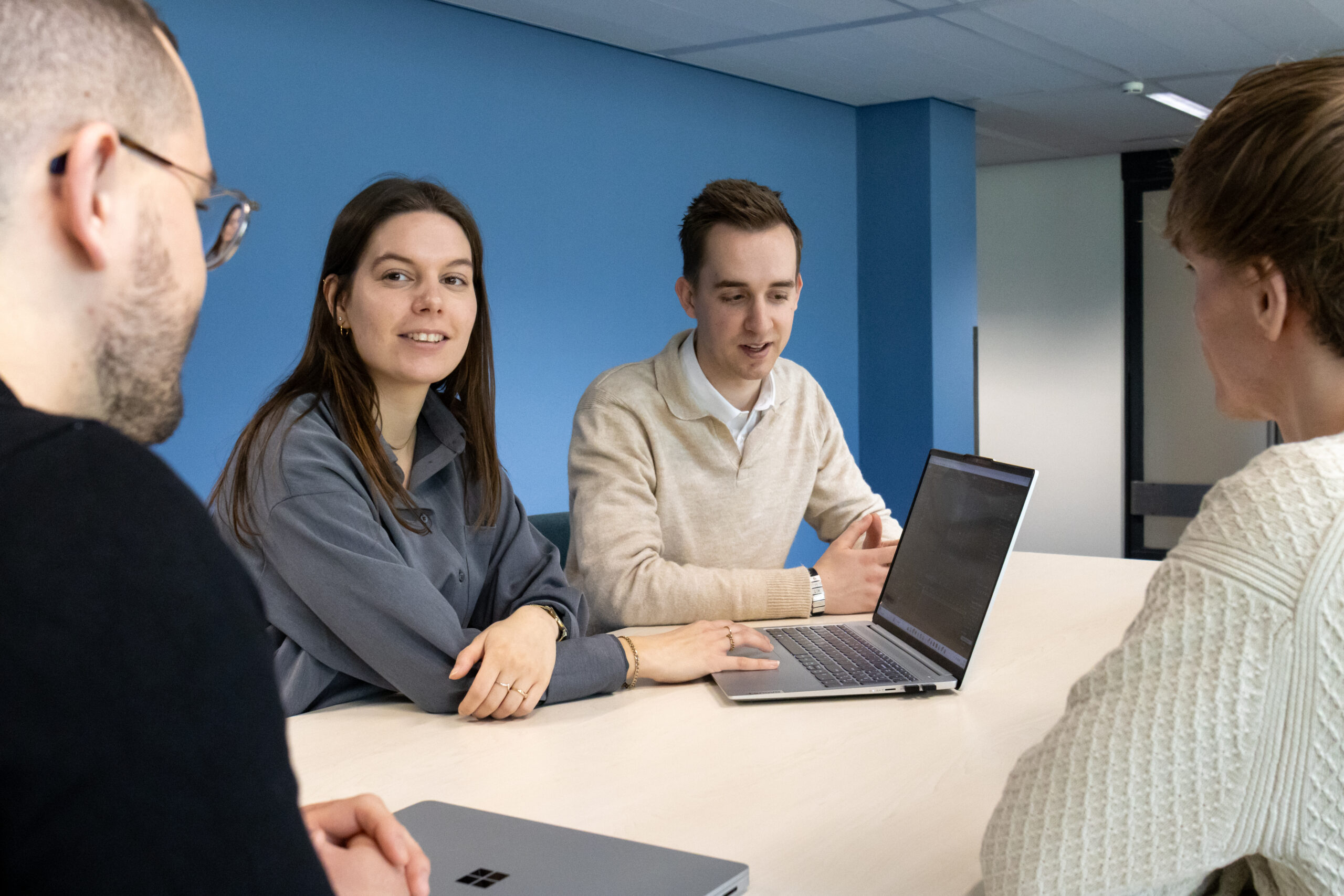 Een sfeerfoto van vier collega's van Univia vergaderend aan tafel met een laptop in het midden